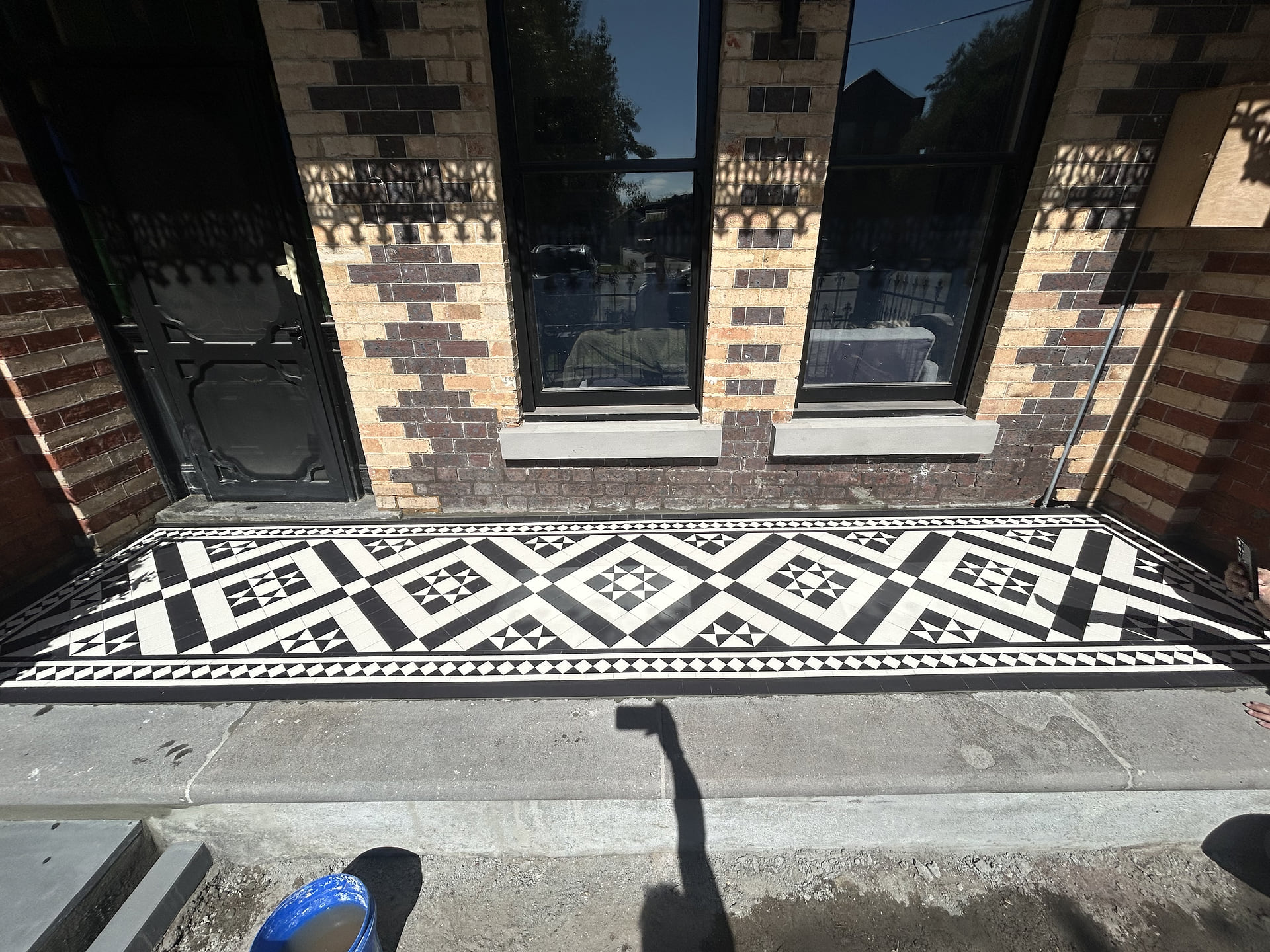 Black and white customised Paddington porch with a Norwood border on a polychrome-brick house, Middle Park