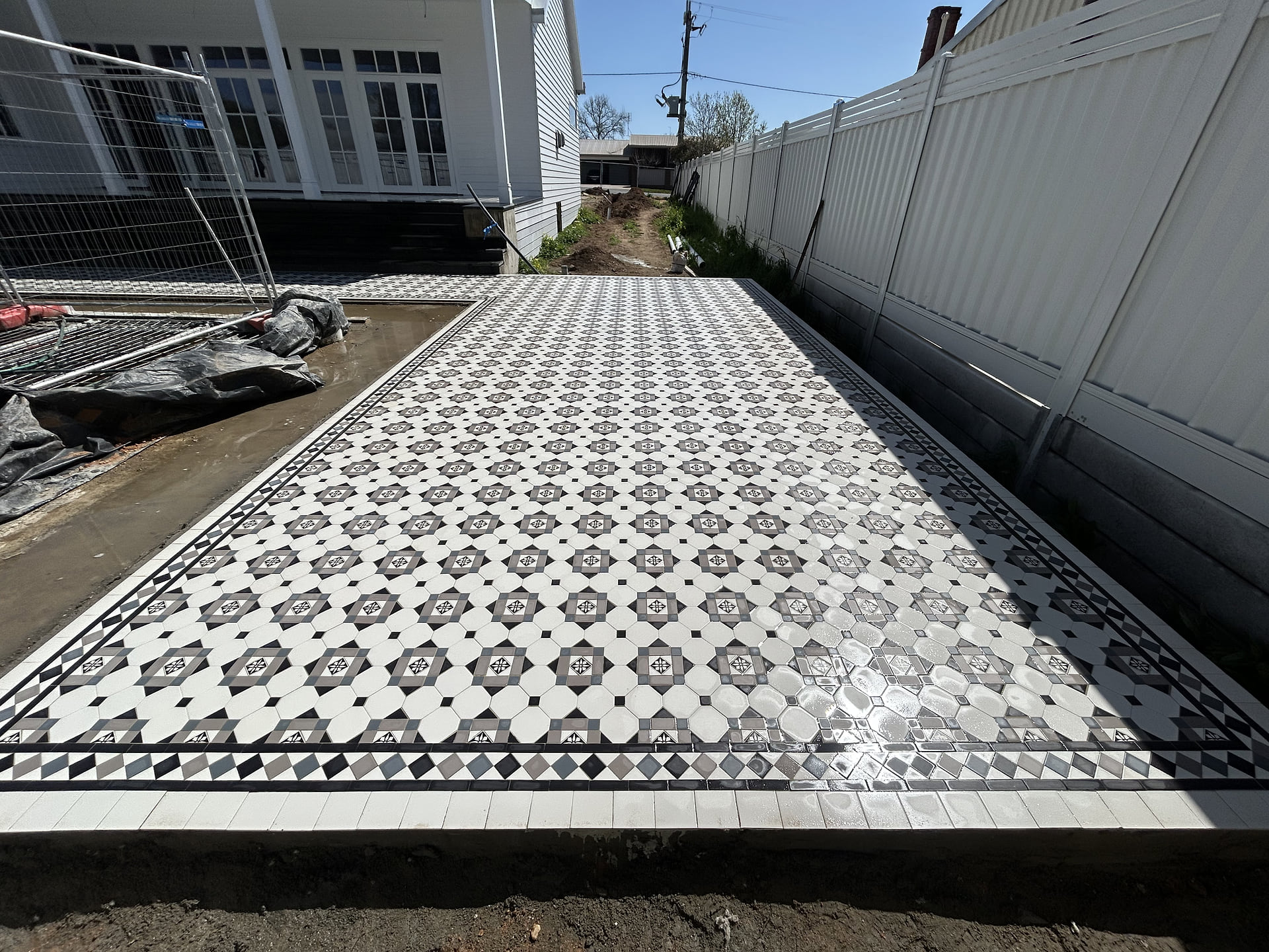 Long wing of a Glasgow tiled verandah on a new-build country house from the yard, St Arnaud
